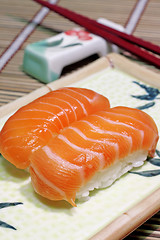 Image showing Yummy salmon. A close-up of chopsticks and a square plate with t