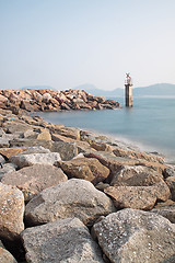 Image showing Lighthouse on a Rocky Breakwall: A small lighthouse warns of a r