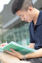 Image showing casual asian businessman texting on his book. 