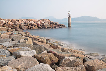 Image showing Lighthouse on a Rocky Breakwall: A small lighthouse warns of a r