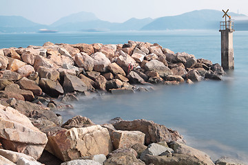 Image showing Lighthouse on a Rocky Breakwall: A small lighthouse warns of a r