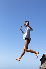 Image showing young man jumping from  the cliff with spreaded hands