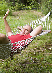 Image showing smiling middle age man relaxing in hammock 