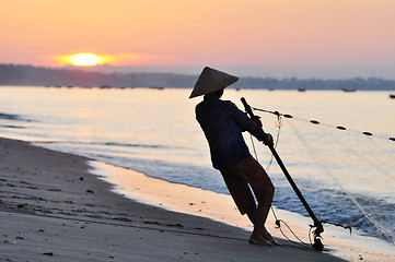 Image showing Silhouette of a fisherman on beach at sunrise