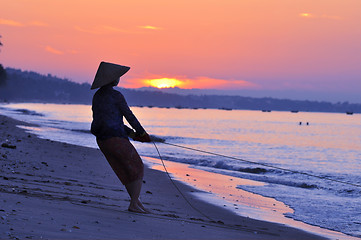 Image showing Silhouette of a fisherman on beach at sunrise