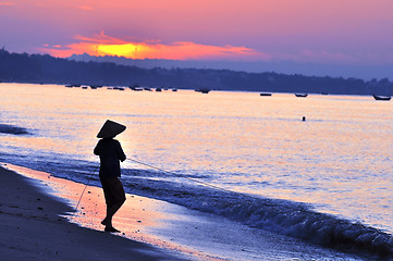 Image showing Silhouette of a fisherman on beach at sunrise