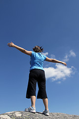 Image showing young woman with arms wide open against blue sky