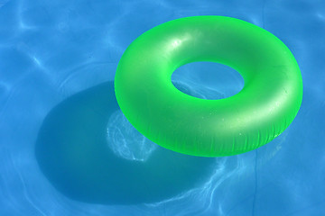 Image showing An inflatable green plastic buoy in a shiny blue swimming pool