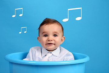 Image showing baby on a blue bucket, studio shoot, listen some musical notes