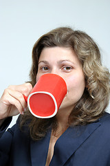 Image showing beautiful woman drinking a red mug of coffee