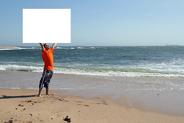 Image showing A handsome man holding a billboard at the beach