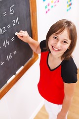 Image showing Schoolgirl looking up in front of chalkboard