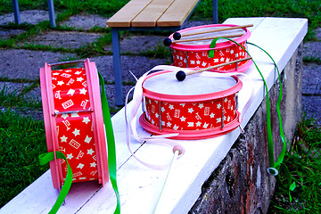 Image showing Pink decorated drums laying on white bench