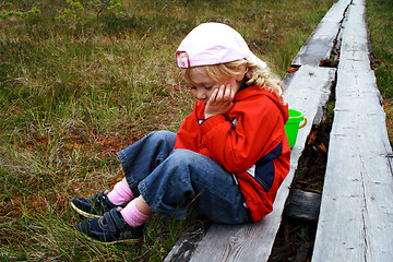 Image showing Girl sitting on whethered bench at park