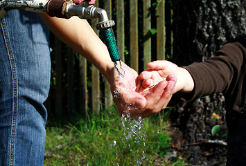 Image showing People washing ditrty hands under water stream