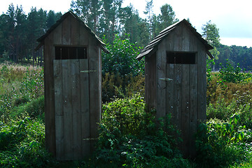 Image showing Wheathered wooden toilets standing in green swamp