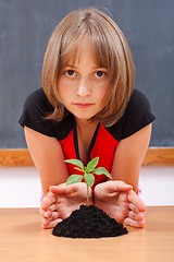 Image showing Serious elementary schoolgirl protecting plant