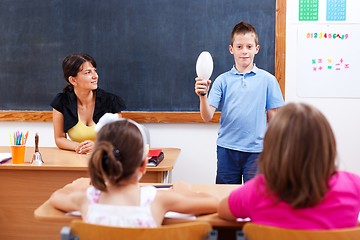 Image showing Schoolboy holding bulb in front of class