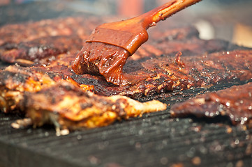 Image showing Basting tasty ribs on the barbeque.