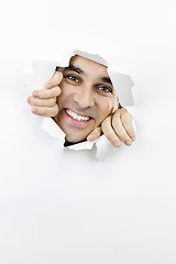 Image showing Happy face looking through hole in paper
