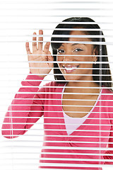 Image showing Smiling woman looking through blinds