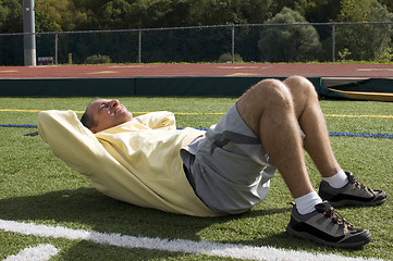 Image showing middle age senior man exercising sit ups ab exercise on sports f