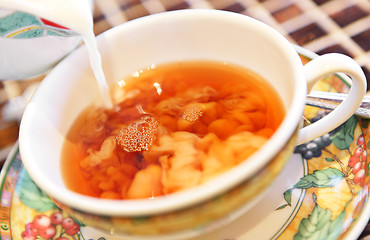 Image showing Pouring milk from jug into cup of tea