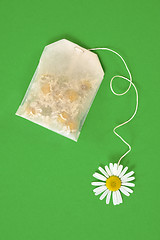 Image showing Bag of chamomile tea over green background - concept