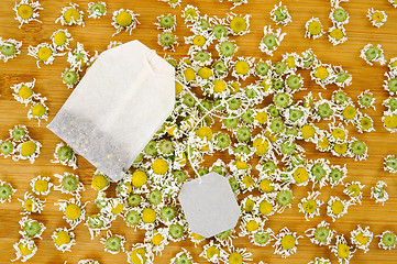 Image showing Bag of chamomile tea with dry chamomilla flowers over wooden background