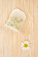 Image showing Bag of chamomile tea over wooden background - concept