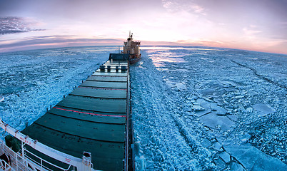 Image showing Icebreaker towing cargo ship through thick ice-field