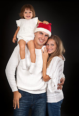 Image showing Father in santa hat holding little girl on his shoulder and hugg