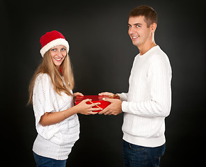 Image showing The man gives the gift pregnant girl in Santa hat