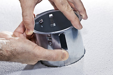 Image showing Hands installing metal pot light fixture