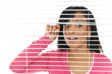 Image showing Woman looking through venetian blinds