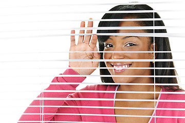 Image showing Smiling woman looking through blinds