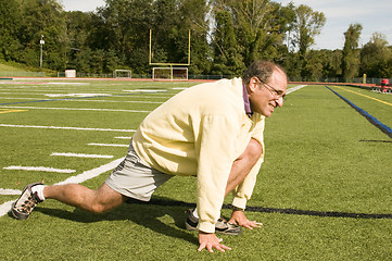 Image showing   middle age senior man stretching exercising on sports field