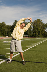 Image showing middle age senior man stretching exercising on sports field