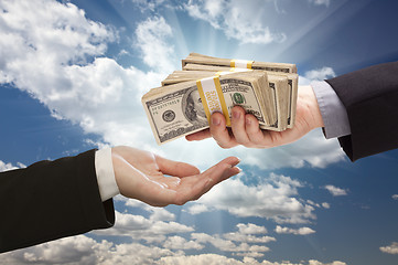 Image showing Handing Over Cash with Dramatic Clouds and Sky