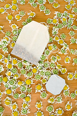 Image showing Bag of chamomile tea with dry chamomilla flowers over wooden background