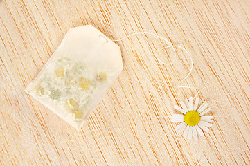 Image showing Bag of chamomile tea over wooden background - concept