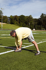 Image showing middle age senior man stretching exercising on sports field