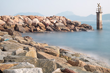 Image showing Lighthouse on a Rocky Breakwall: A small lighthouse warns of a r