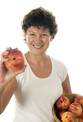 Image showing excited middle age senior woman with fresh peaches fruit