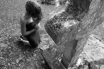 Image showing Woman kneeling in front of a stone cross