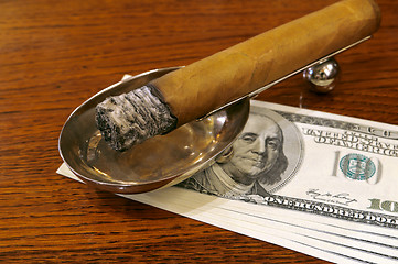 Image showing Cigar on a stand with money