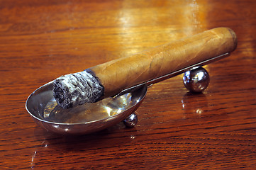 Image showing Cigar on a stand on a wooden background