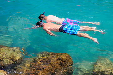 Image showing Two tourists snorkeling in clear sea water.
