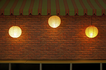 Image showing Brick wall with three illuminated lamps