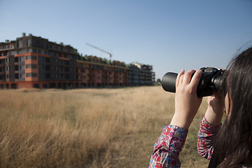 Image showing Woman watching with binoculars building construction